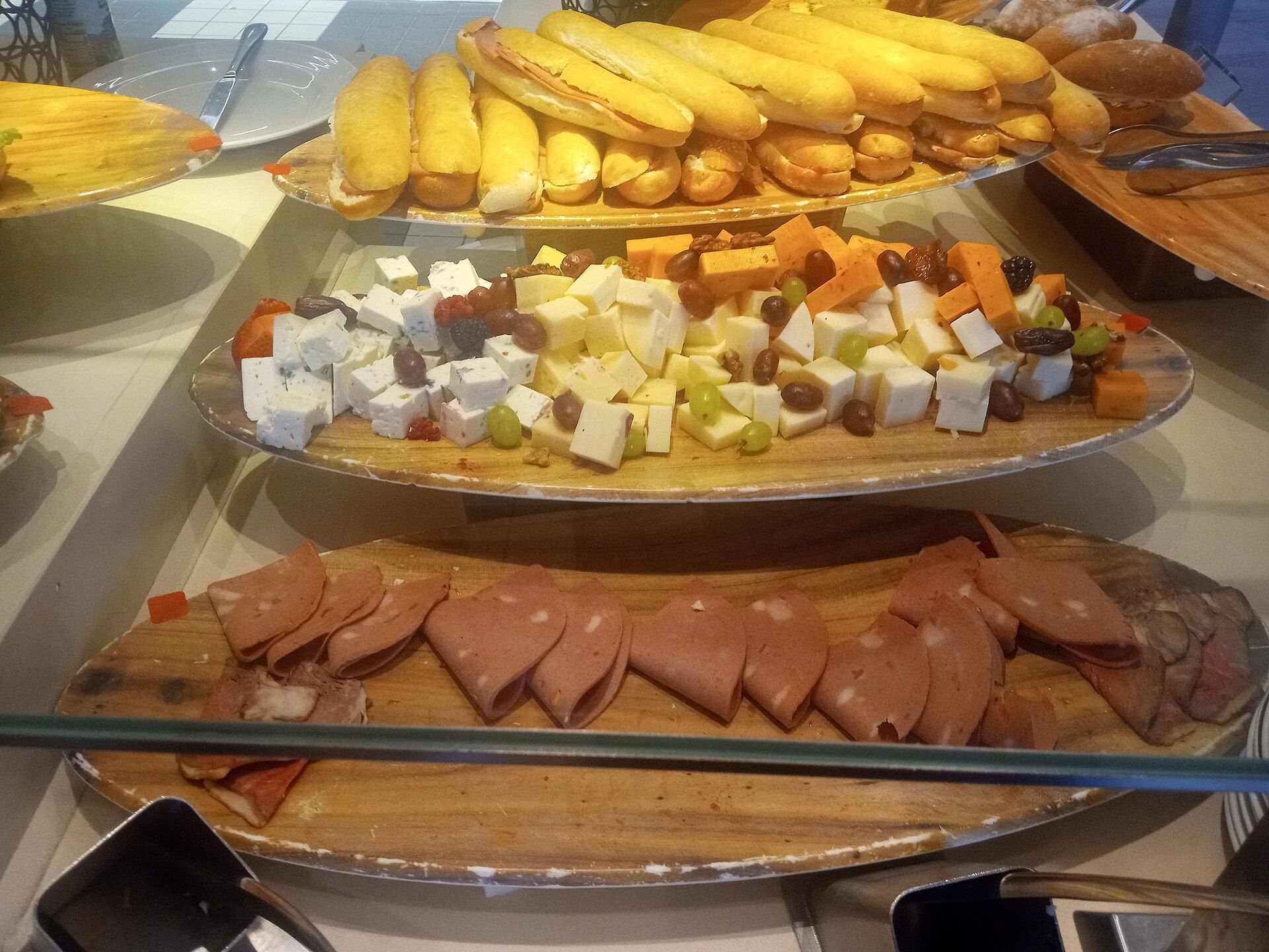 Deli section of a cruise ship buffet with cold cuts, cheese and sandwiches